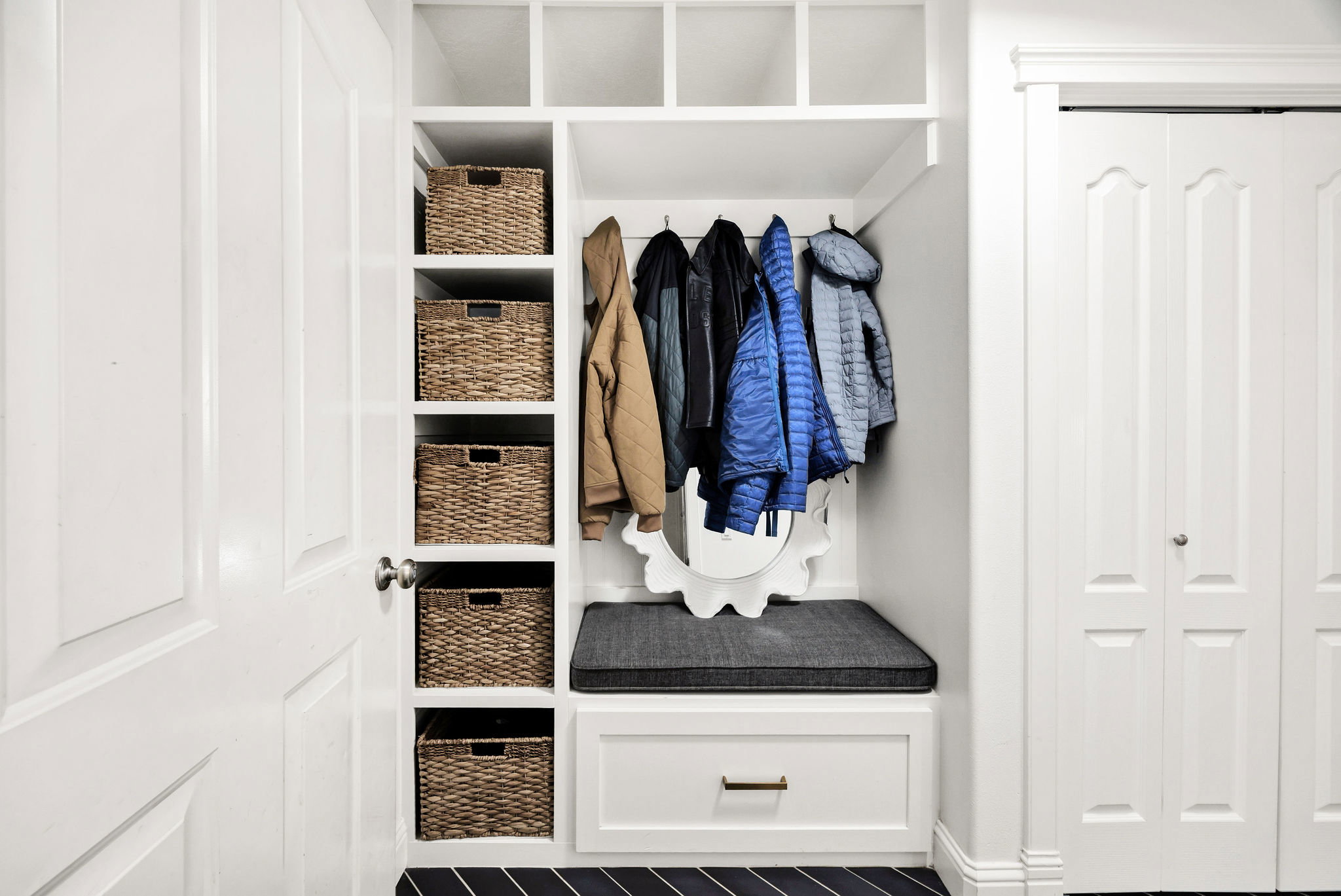 Built-in hall tree featuring upper cubbies, coat hooks, and a cushioned bench with storage drawer
