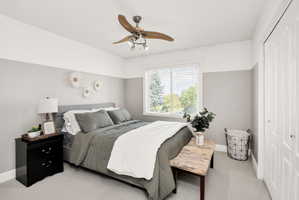 Carpeted room featuring a ceiling fan with integrated lighting, a window with horizontal blinds, and a paneled bifold closet door
