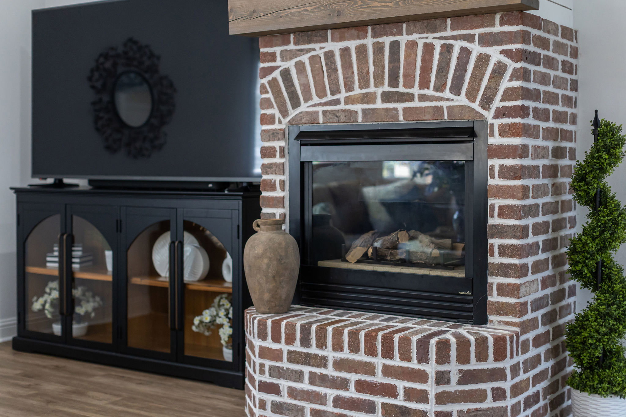 Exposed brick fireplace featuring an arched brick surround and dark metal insert