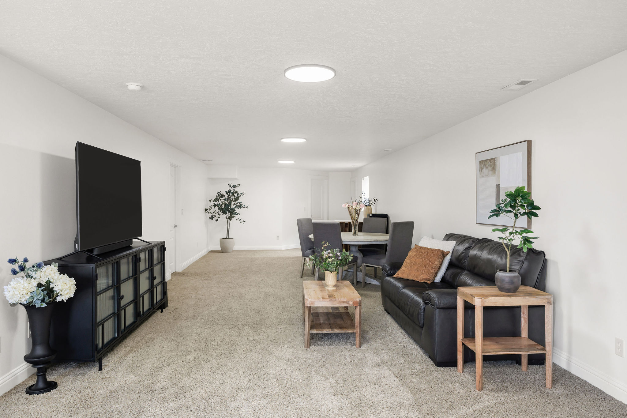Open-concept living area featuring light-toned carpet flooring and white walls