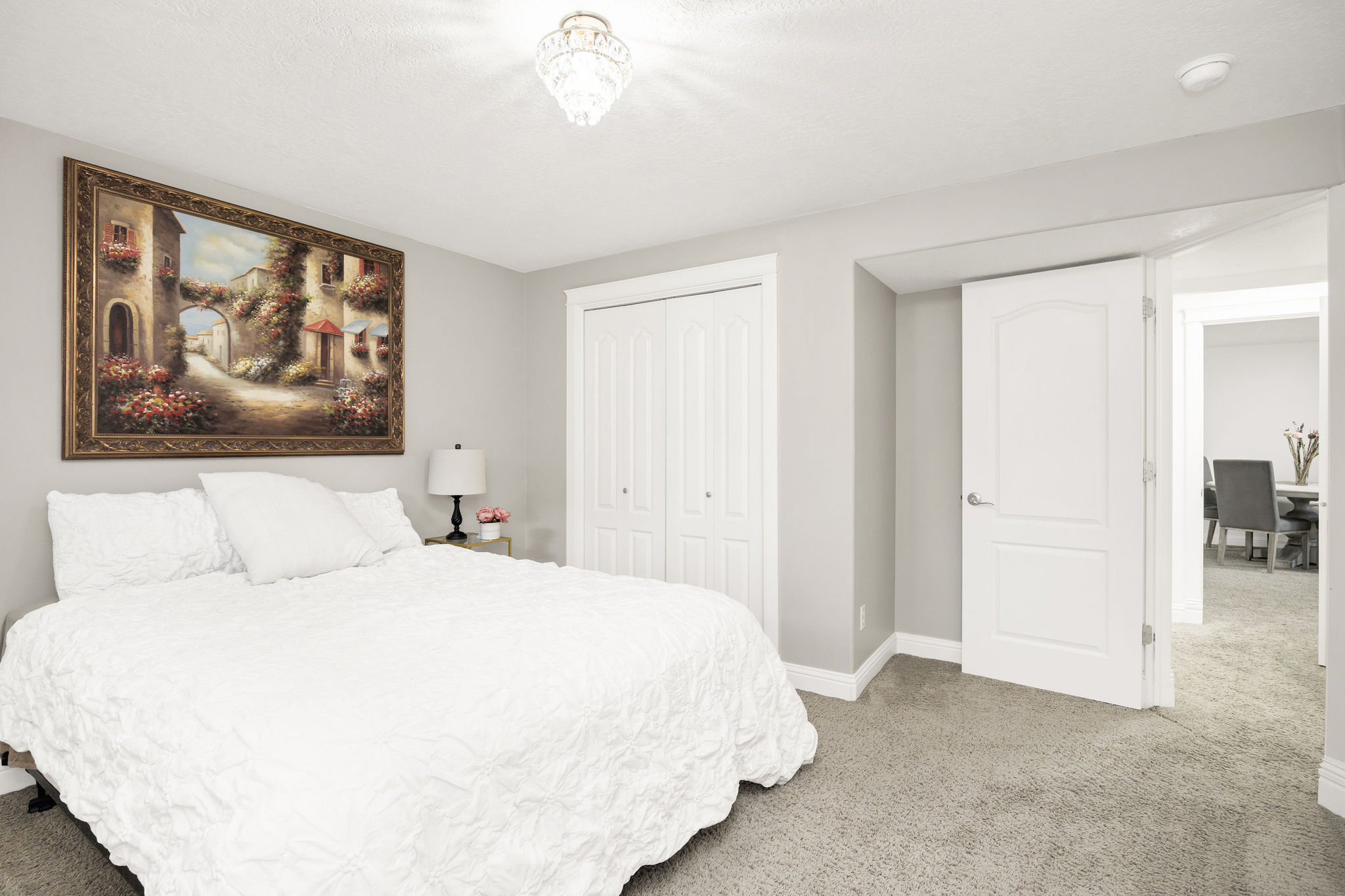 Carpeted room featuring light gray walls, a white bi-fold closet, a white paneled door, and an overhead crystal light fixture