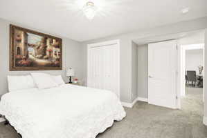 Carpeted room featuring light gray walls, a white bi-fold closet, a white paneled door, and an overhead crystal light fixture