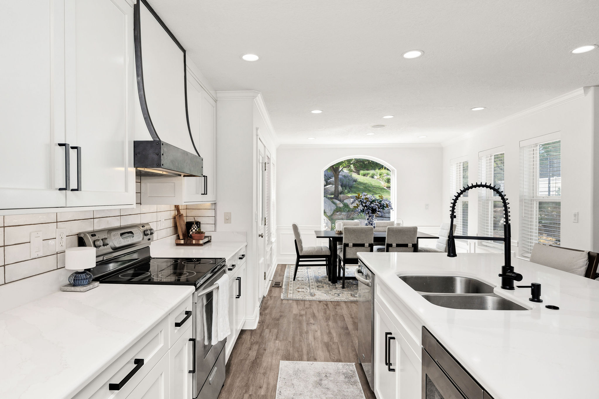 White cabinetry with matte black hardware, a custom range hood, subway tile backsplash, and white countertops