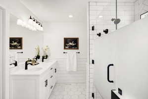 Spacious bathroom featuring a dual vanity with white cabinetry and countertops, matte black faucets, and a large mirror