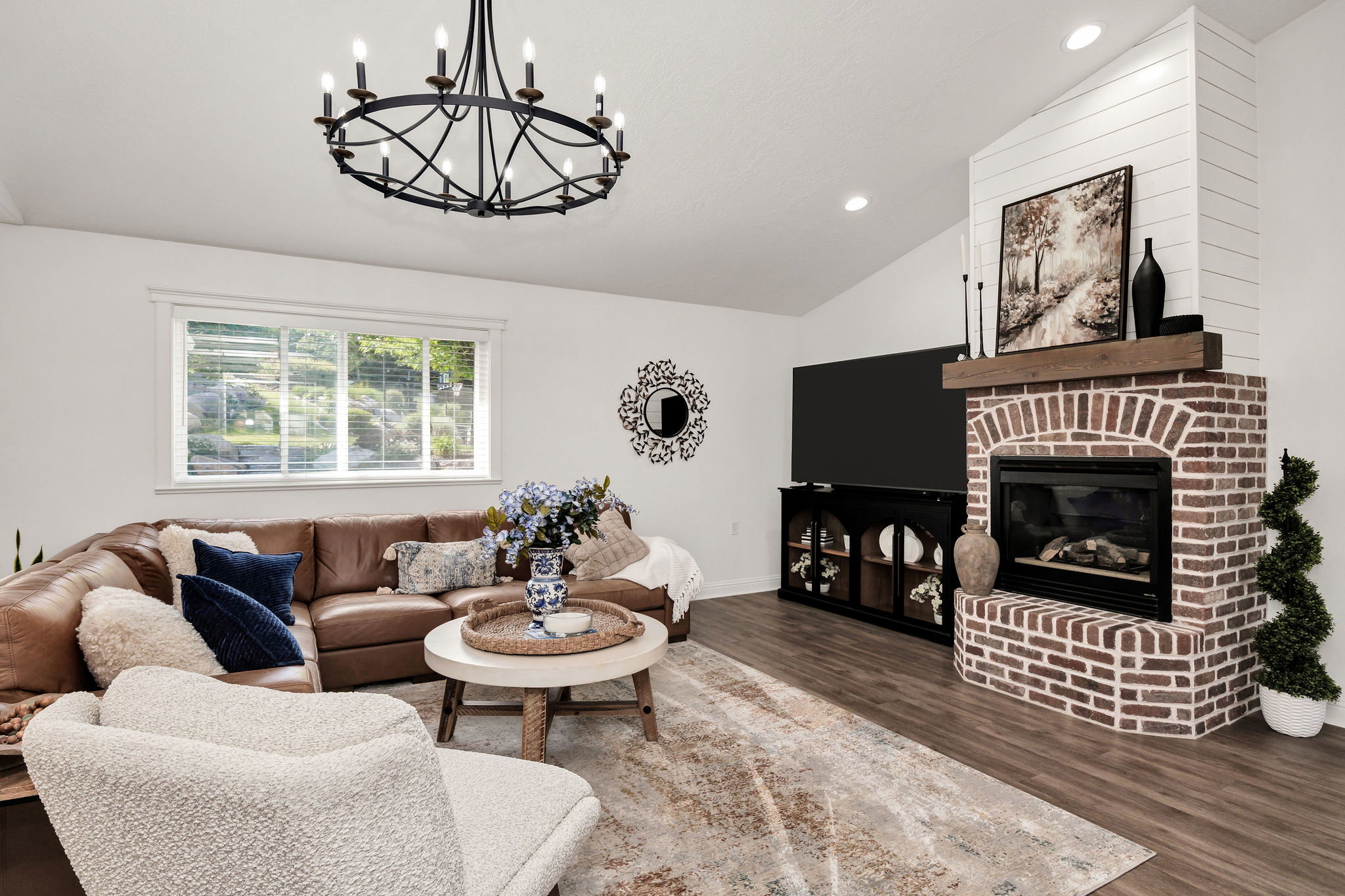 Living area featuring a brick fireplace with a wood mantel, shiplap accent wall, and vaulted ceiling