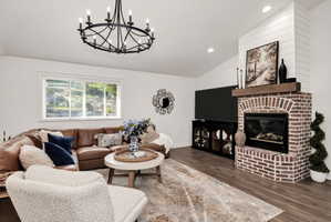 Living area featuring a brick fireplace with a wood mantel, shiplap accent wall, and vaulted ceiling