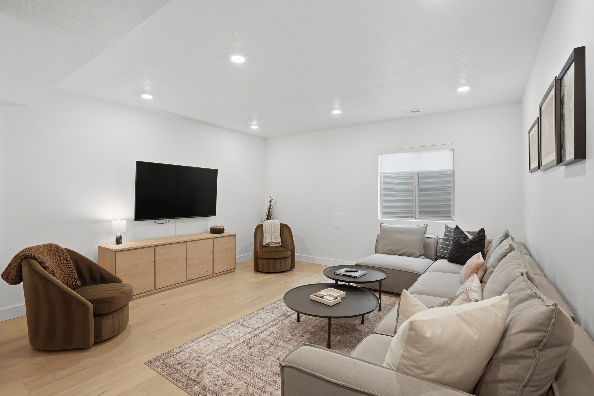 Spacious living area featuring light wood-finish flooring and recessed lighting