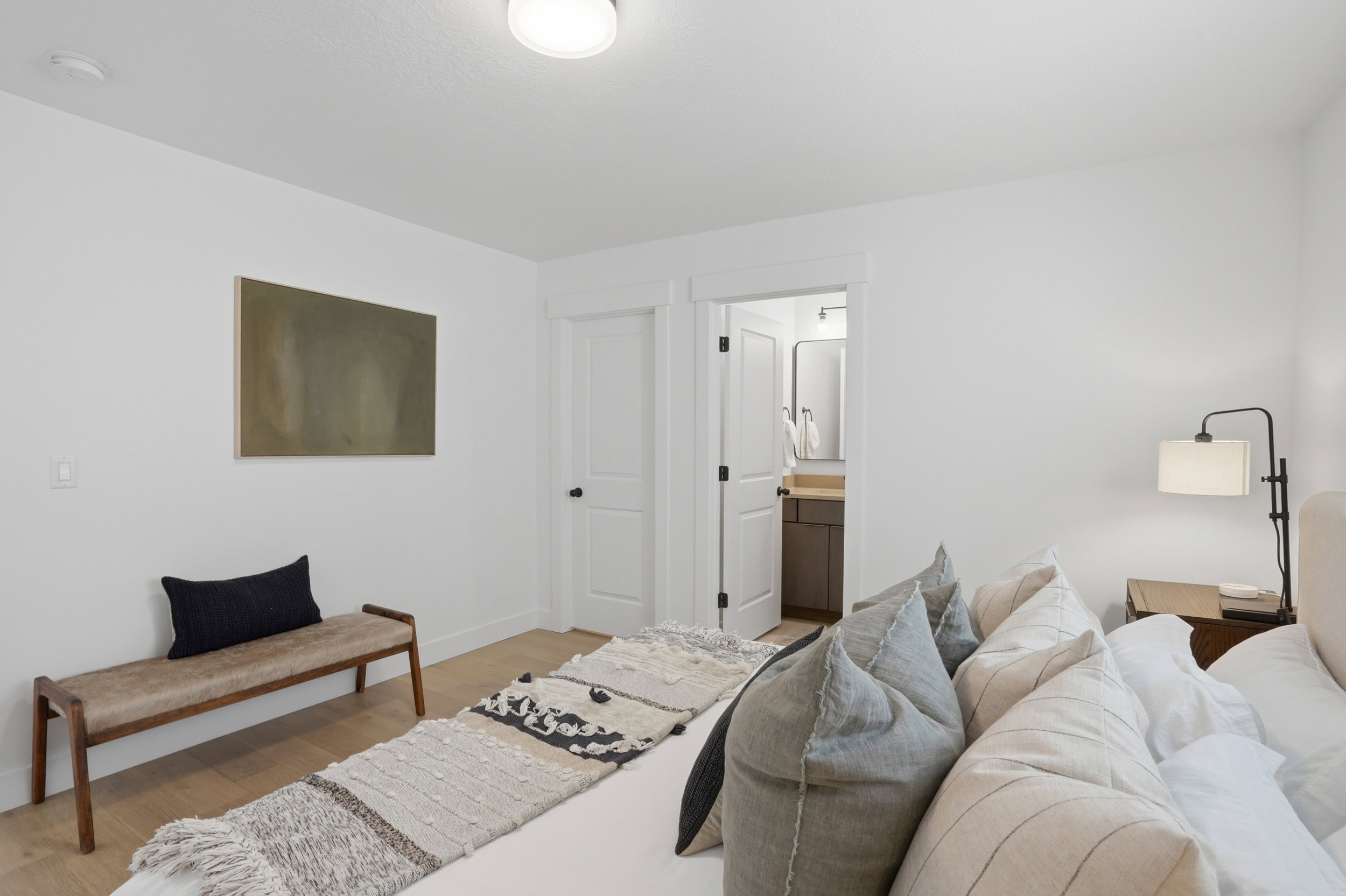 Bright bedroom featuring light wood-finish flooring and a white color palette