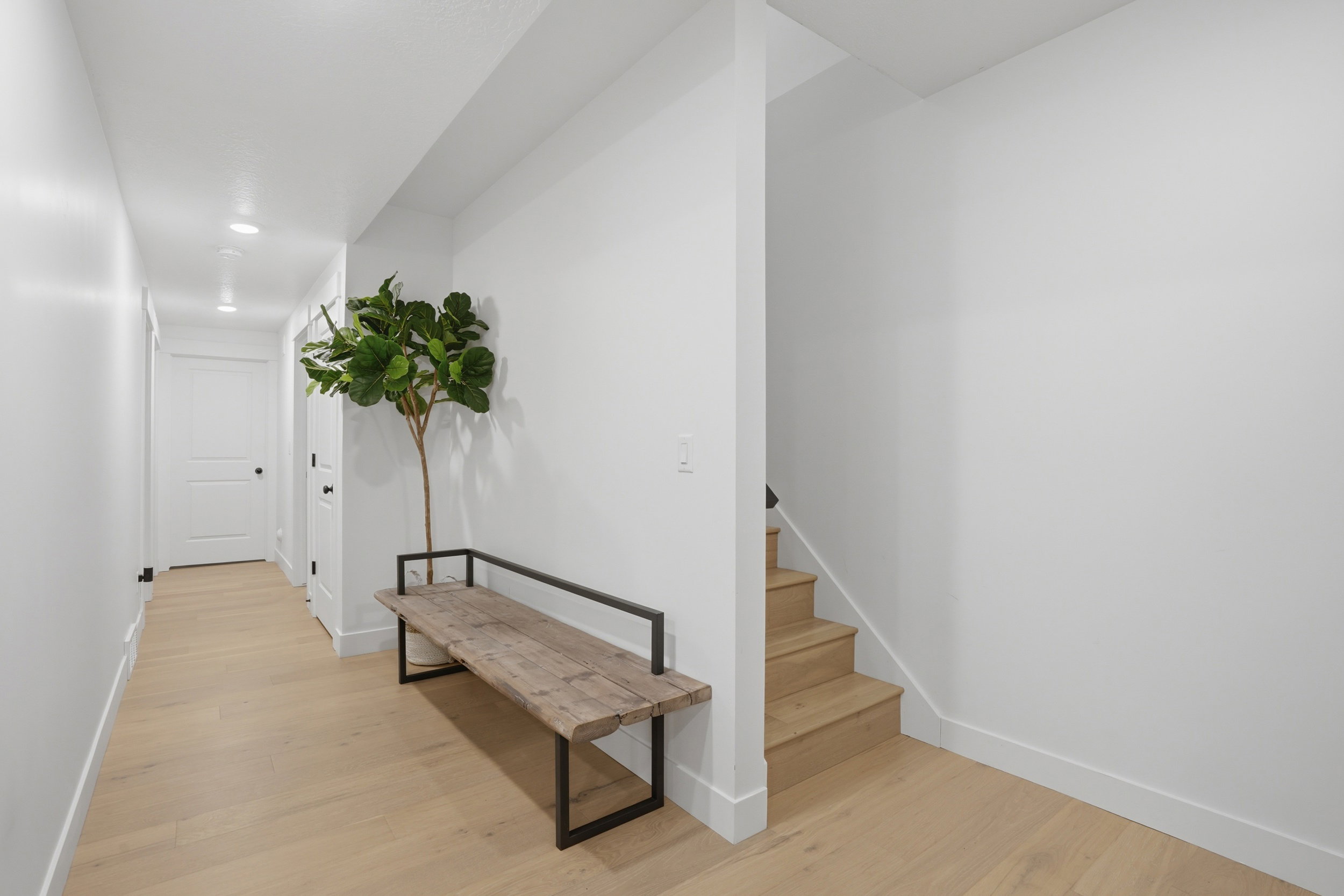 Hallway entry featuring light wood-finish flooring, white walls, recessed lighting, and a staircase with wood-finish treads