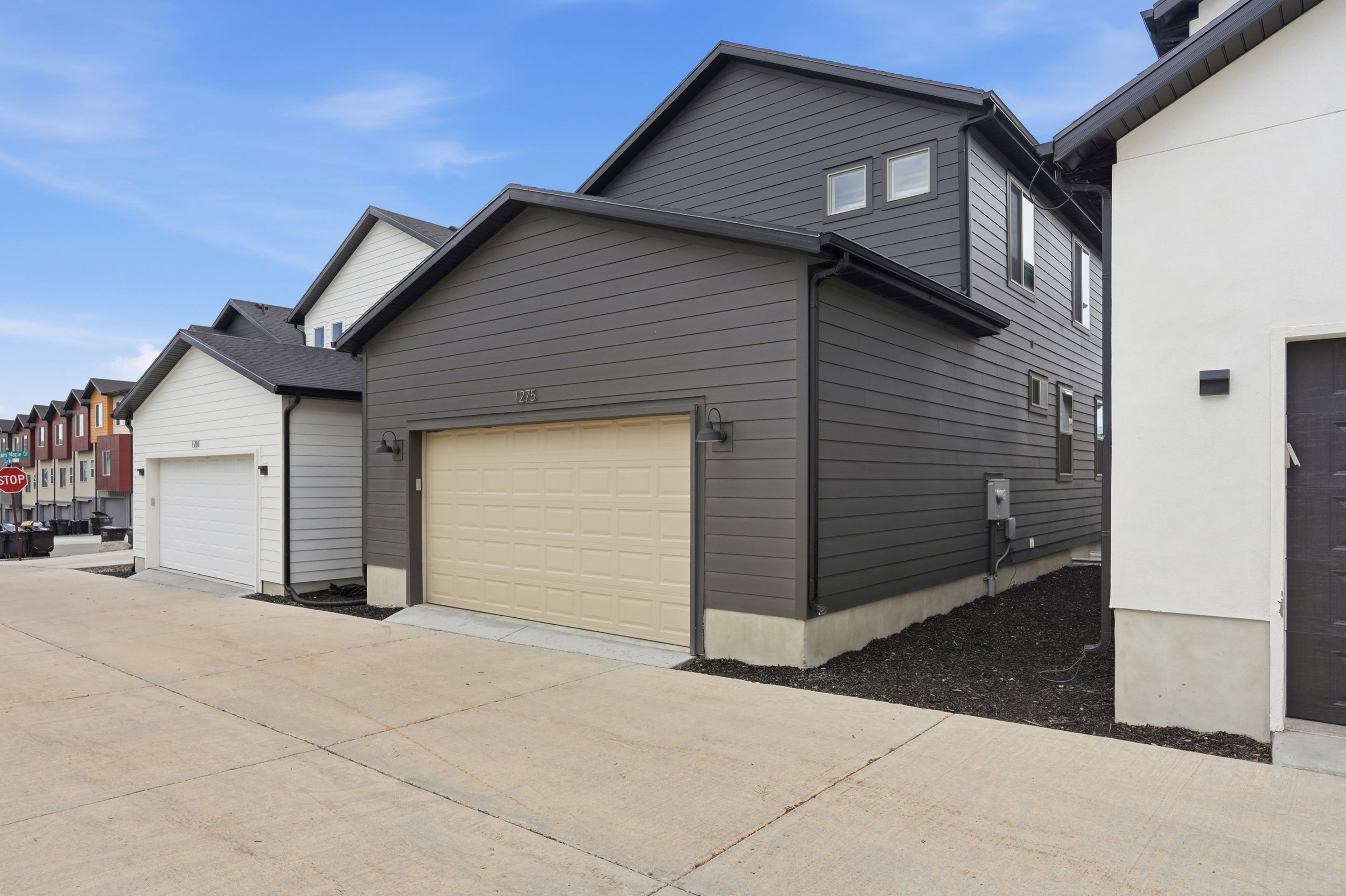 Contemporary dark gray siding residence featuring a tan garage door, black trim, and architectural shingles