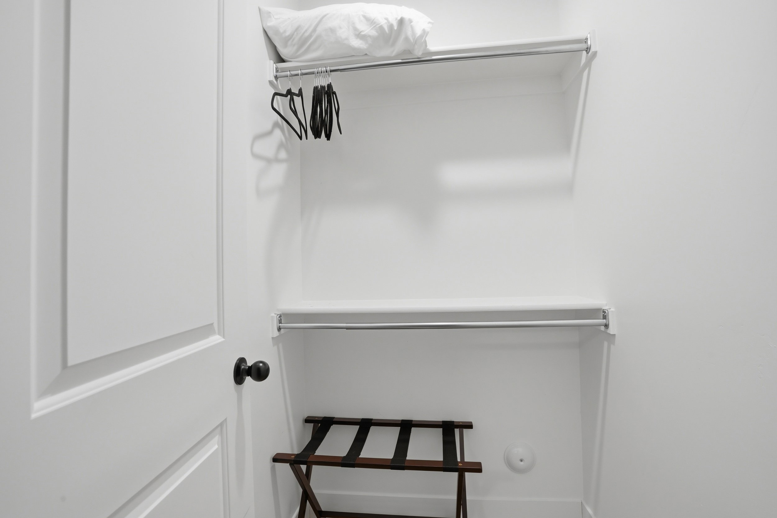 Closet with white walls, two levels of shelving, and two clothing rods