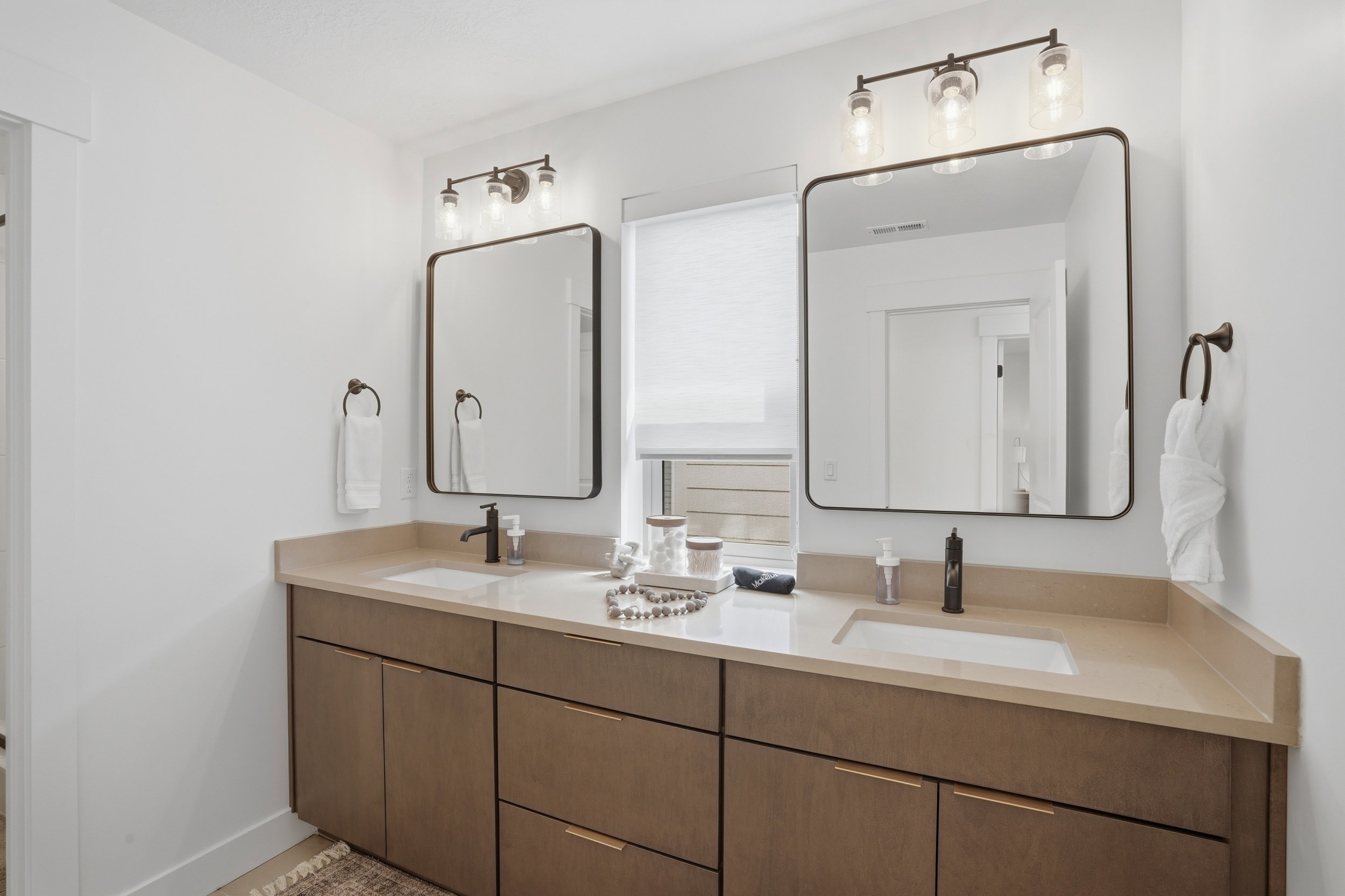 Dual vanity featuring wood-finish cabinetry and light-toned countertops