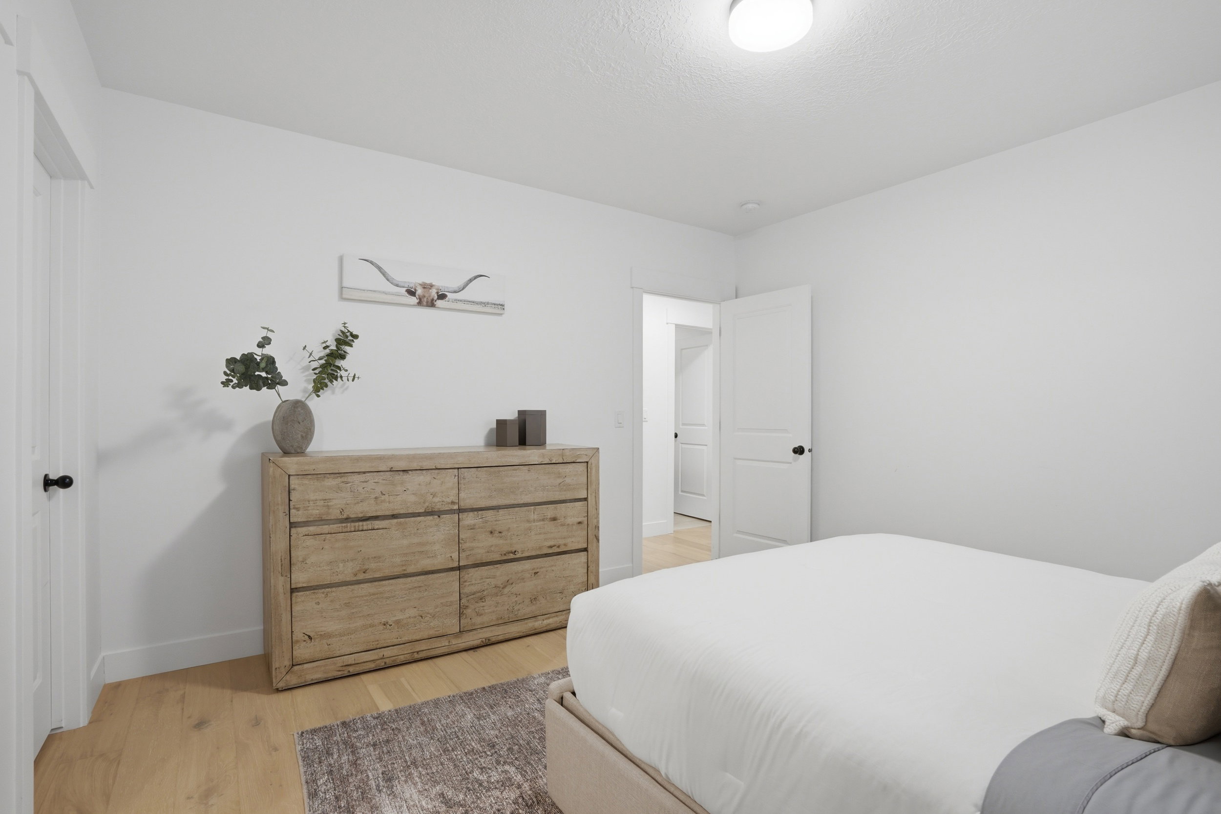Bright interior space featuring light-toned wood-finish flooring, white walls, and contemporary black door hardware