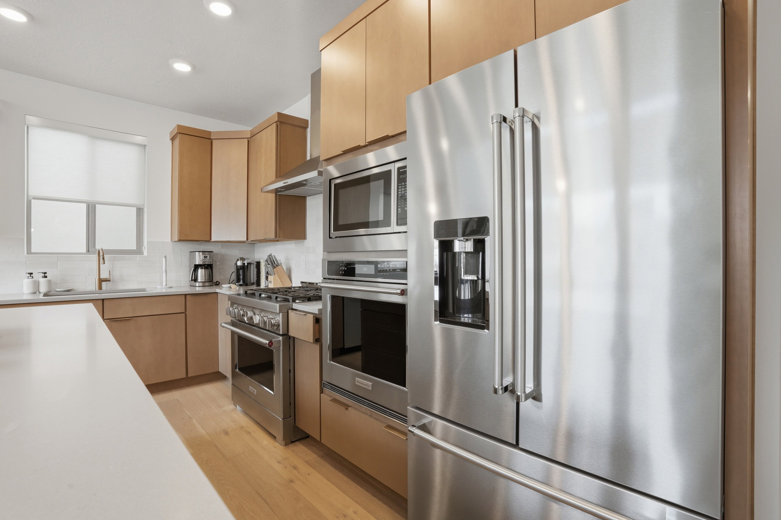 Kitchen featuring stainless steel appliances, light wood-finish cabinetry, white countertops, and recessed lighting
