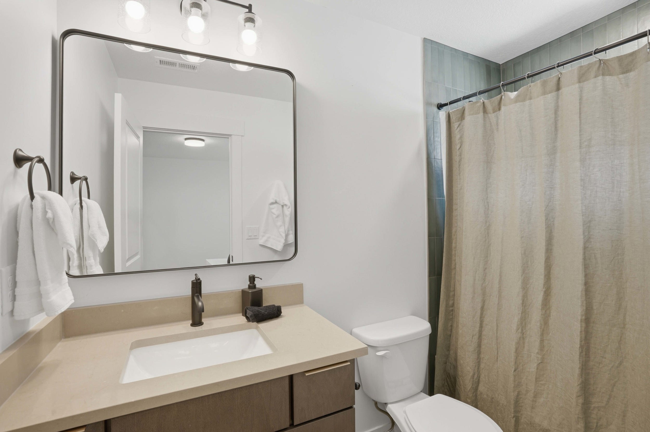 Bathroom featuring a vanity with an integrated sink, a dark bronze faucet, and a large framed mirror