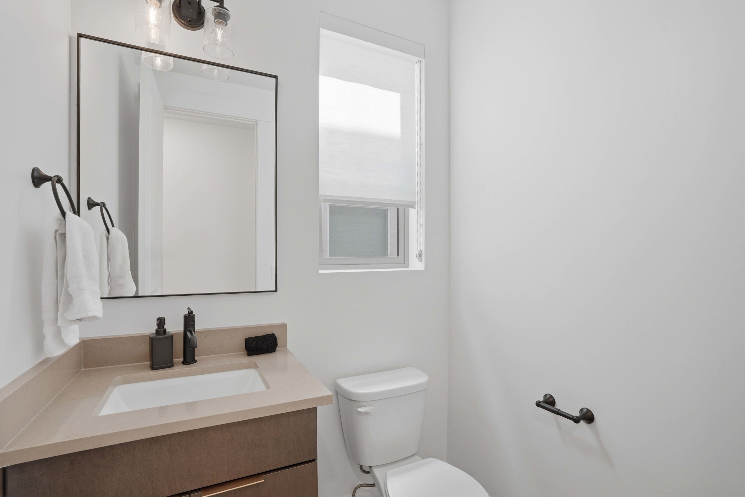 Contemporary vanity with an integrated sink, light-toned countertop, and matte black hardware
