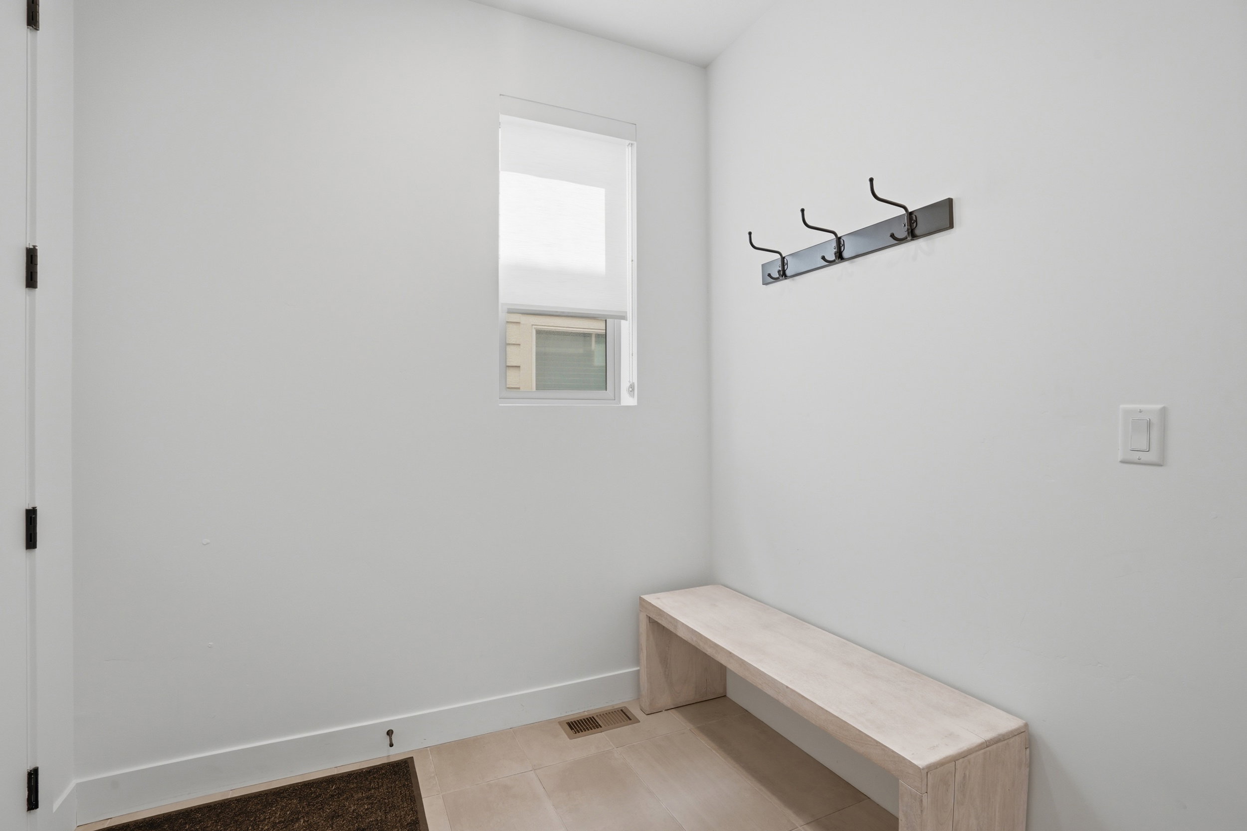 Entryway featuring a built-in bench, integrated coat rack, and tiled flooring