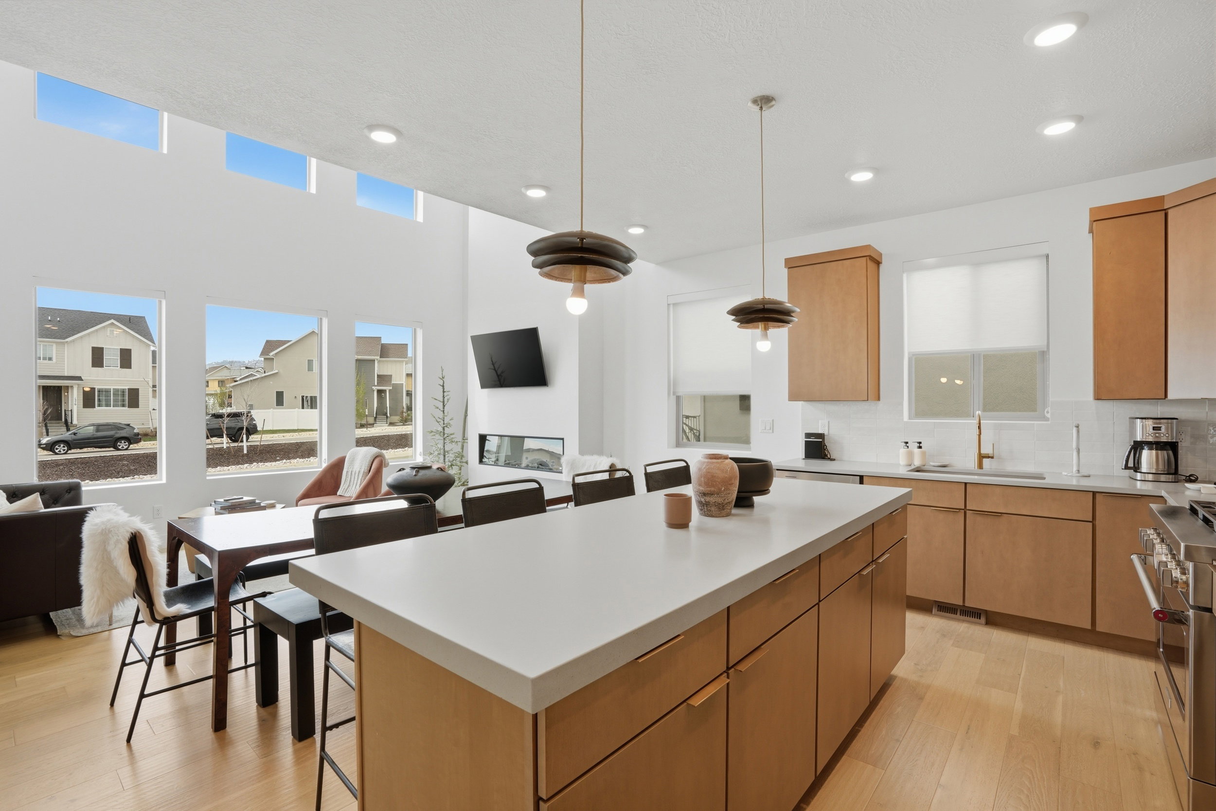 Open-concept kitchen and dining area featuring light wood-finish flooring, a kitchen island with a light-toned countertop, and recessed ceiling lighting