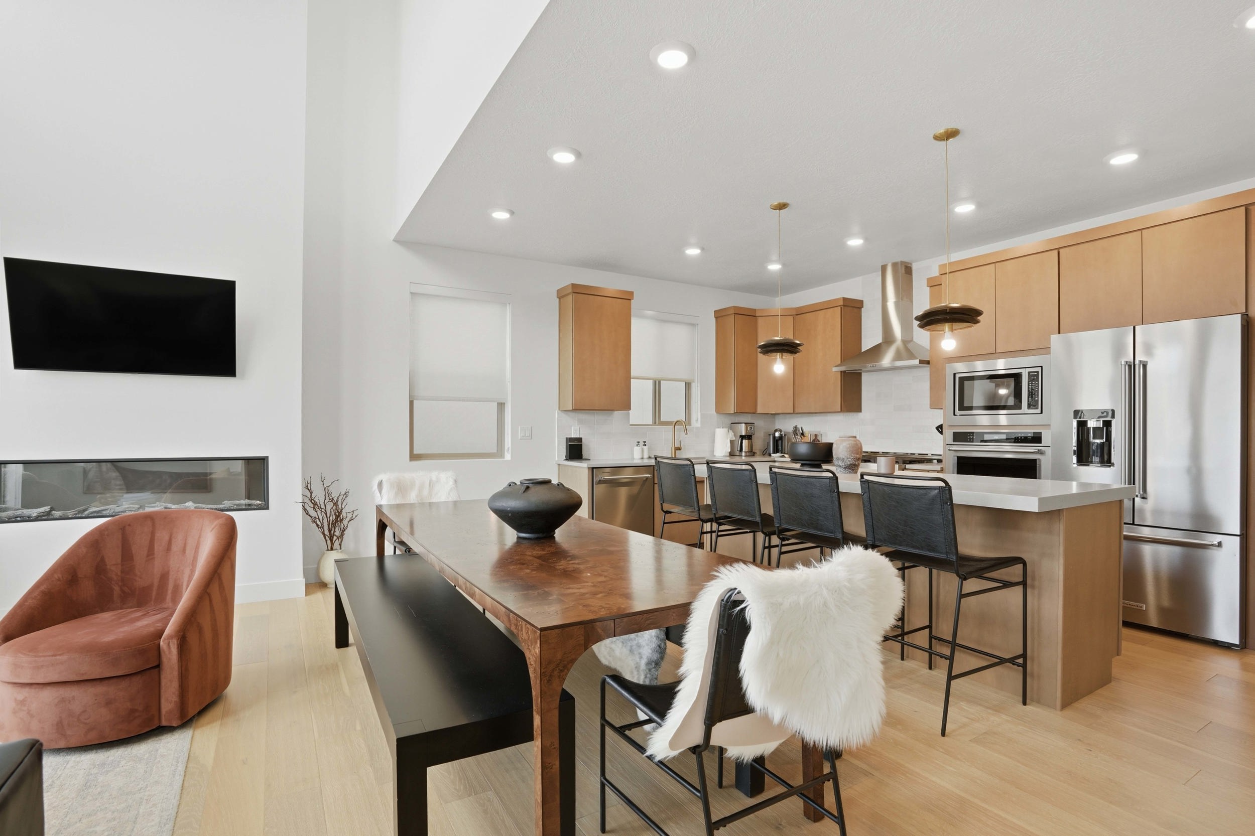 Open-concept living space with a contemporary kitchen featuring light wood cabinetry and stainless steel appliances