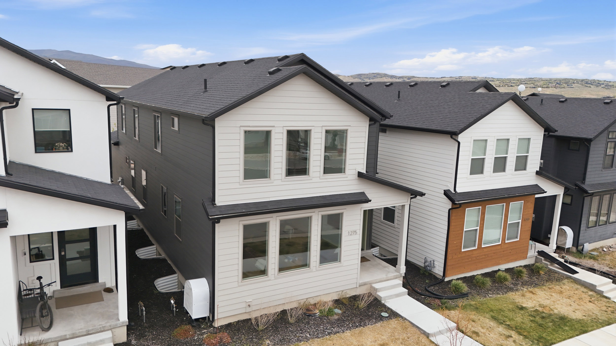 Contemporary two-story exterior featuring white and dark gray siding, black trim, and a covered front porch