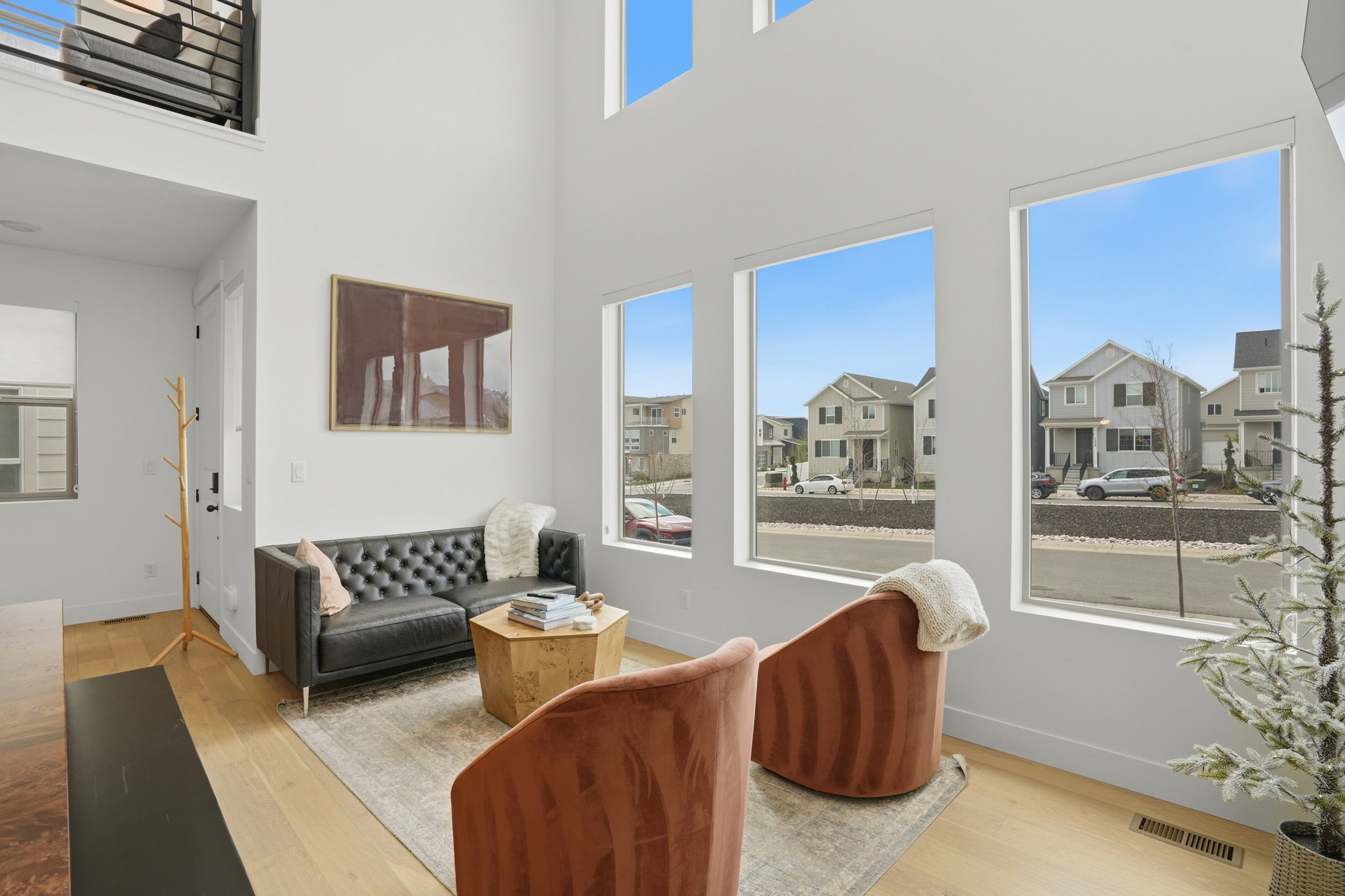 Living area featuring a two-story ceiling, light wood-finish flooring, and multiple large windows