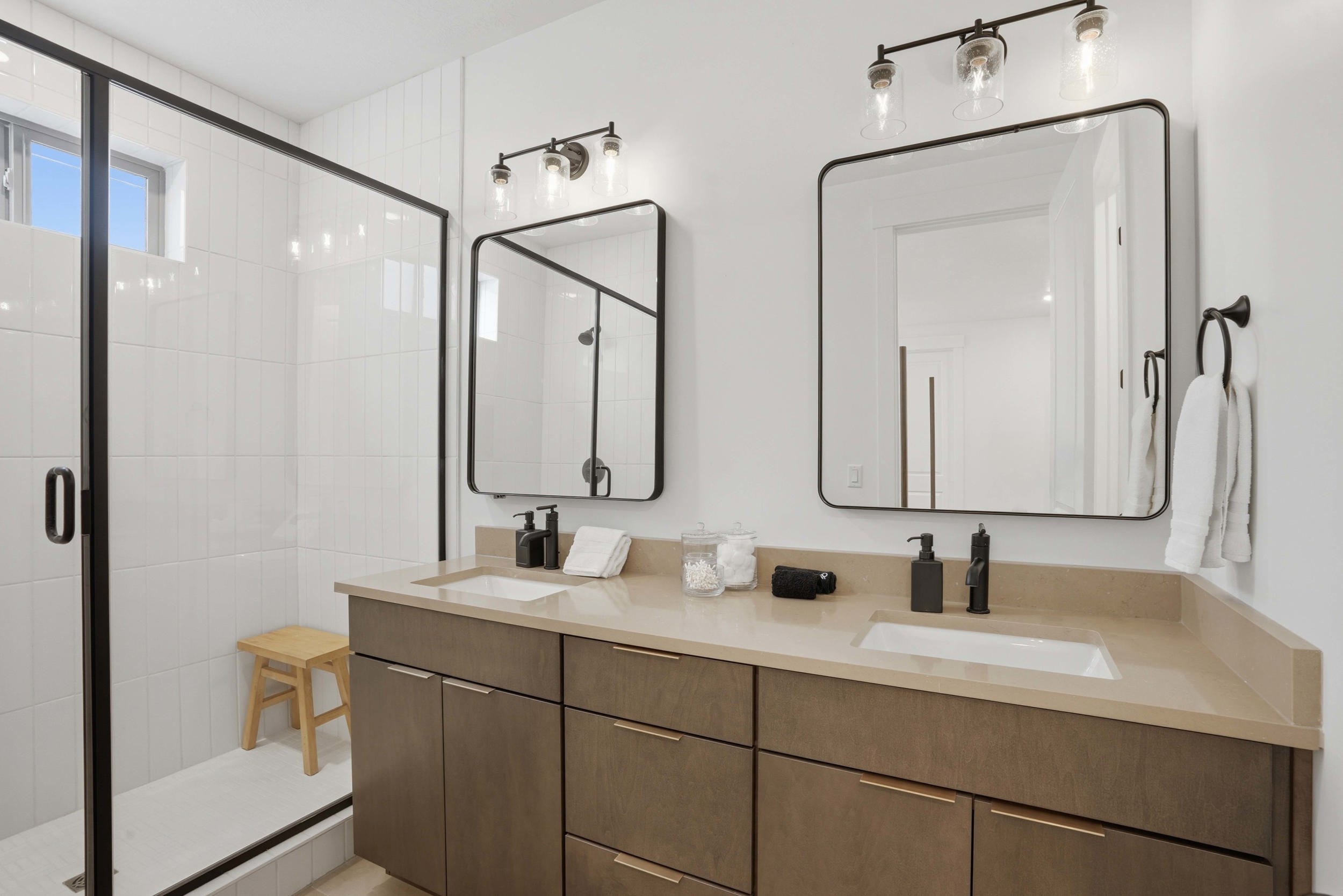 Double vanity with integrated sinks, light-toned countertop, and wood-finish cabinetry featuring gold-tone hardware