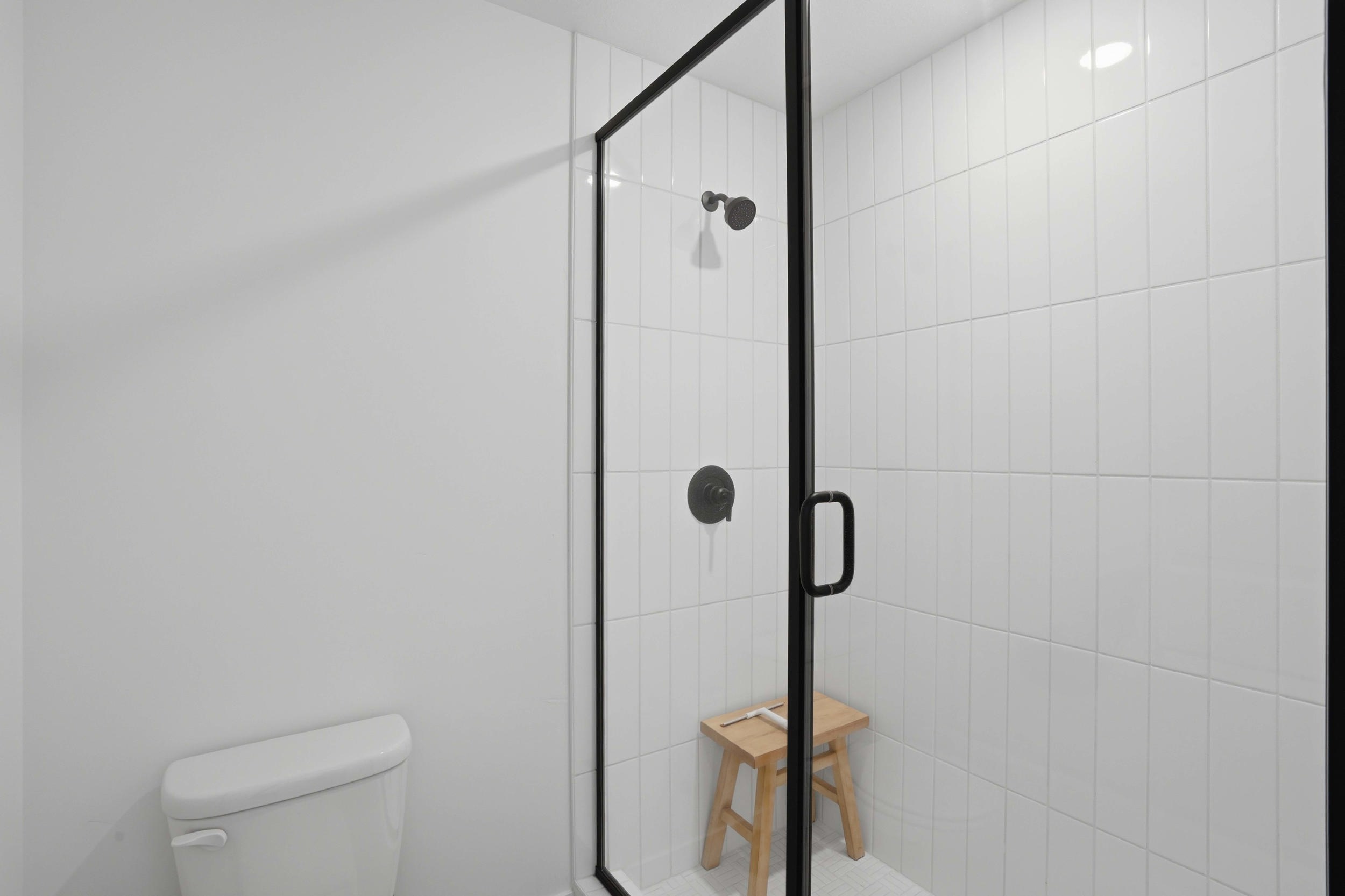 Modern shower enclosure featuring a frameless glass door with matte black trim and hardware
