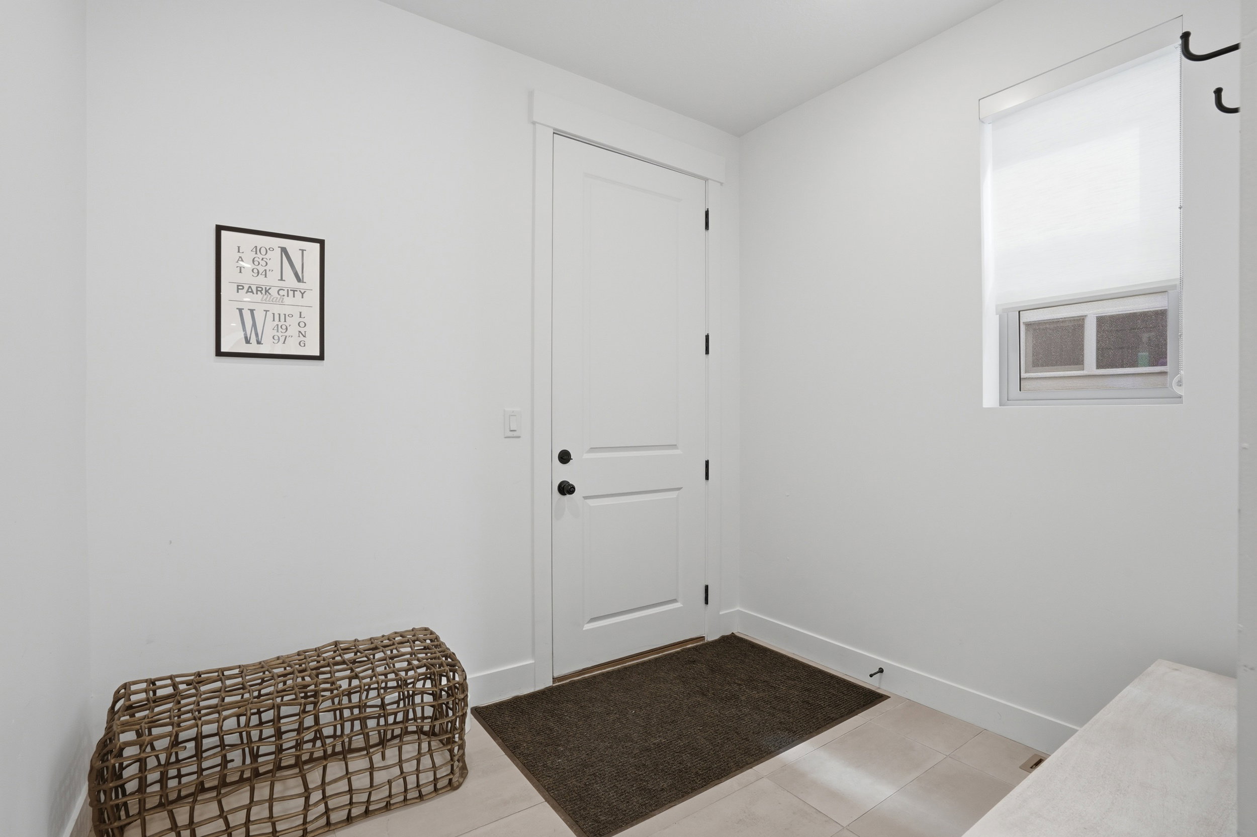 Entryway featuring a white paneled door with black hardware, light-colored floor tiles, and white baseboards