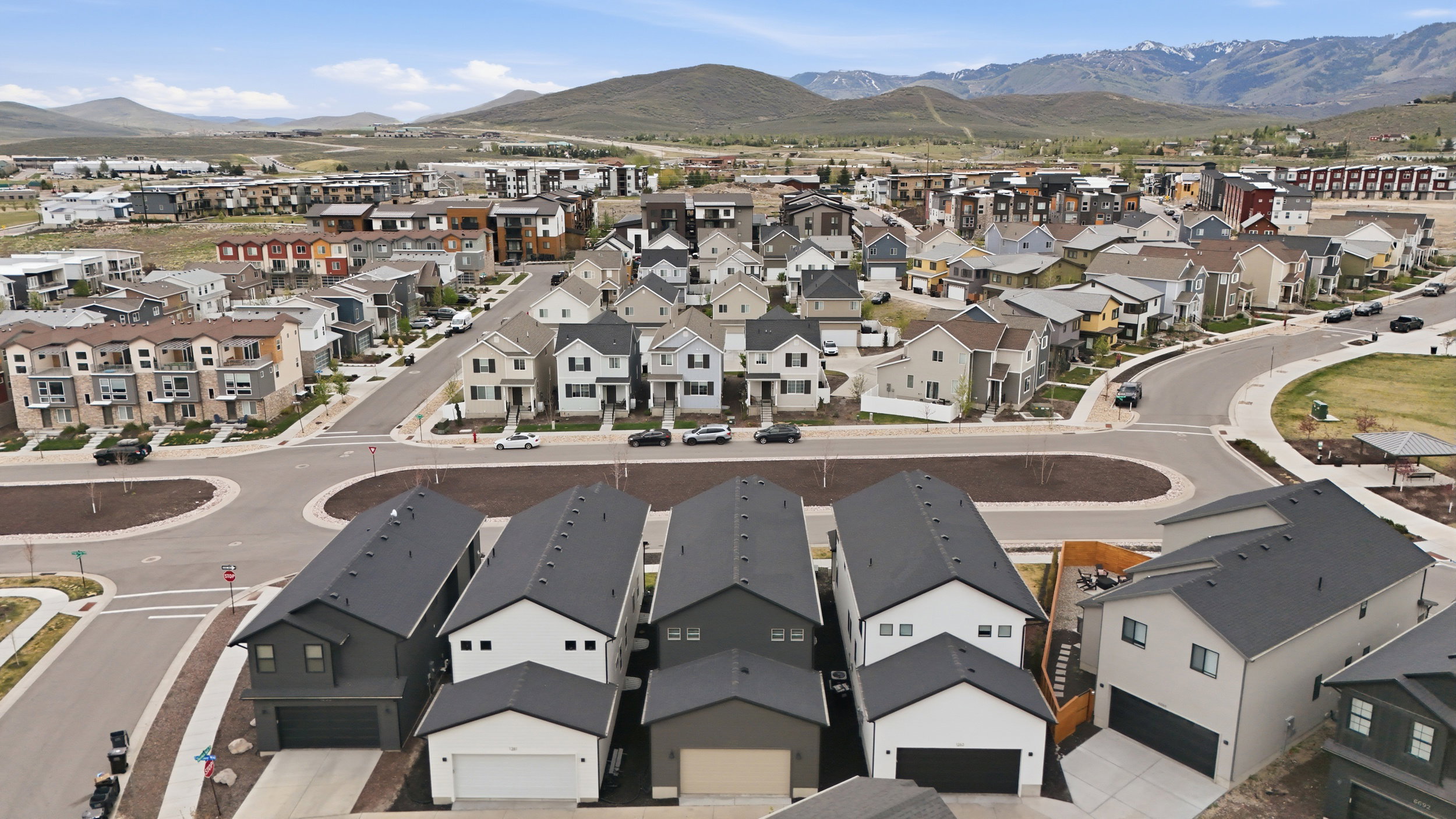 Modern residential development with varied architectural styles, a paved street grid, and circular landscaping features