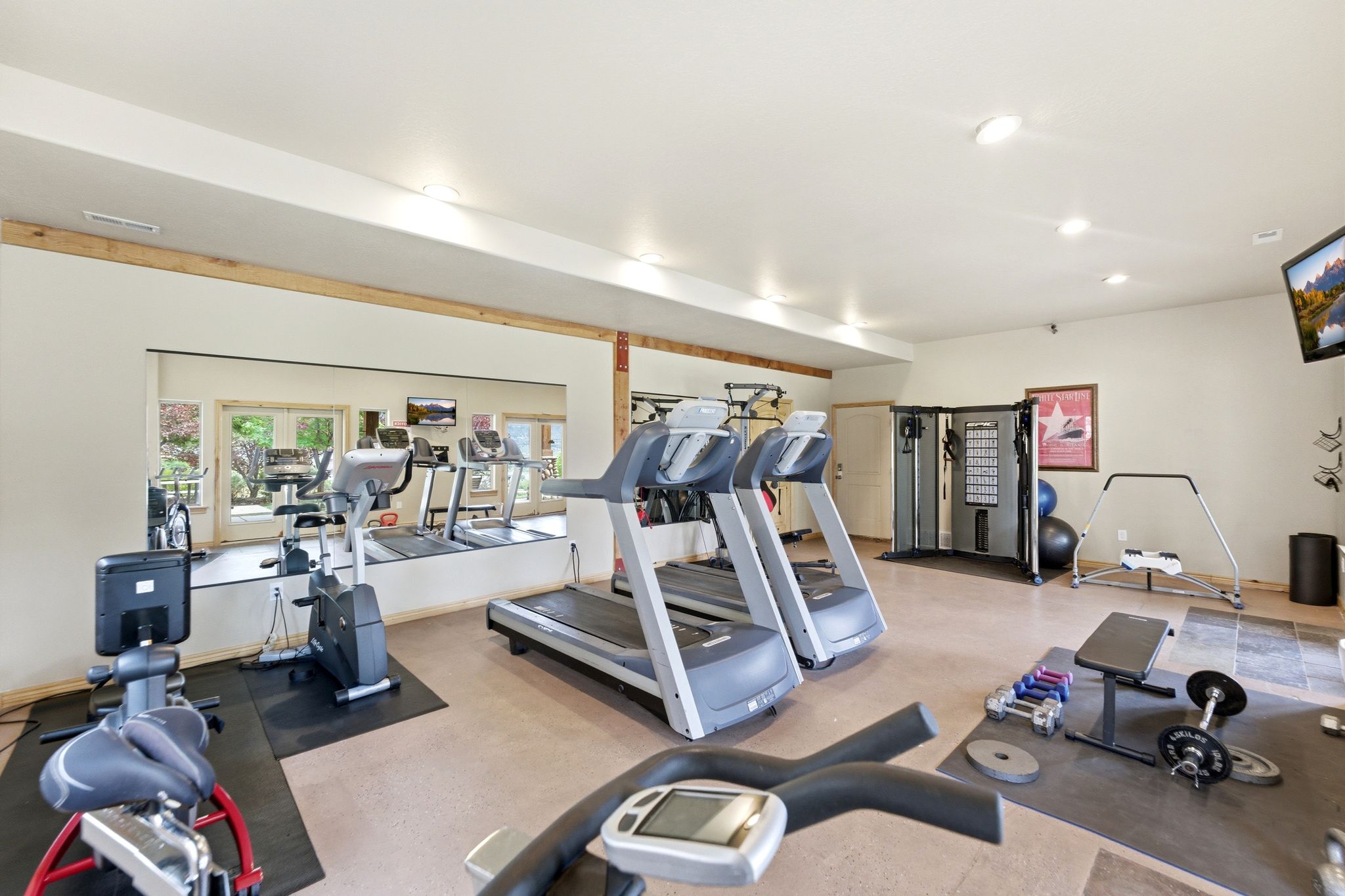 Dedicated fitness area featuring extensive wall mirrors, neutral-toned flooring, recessed lighting, and a built-in multi-gym system