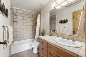 Bathroom featuring a built-in wood vanity with tile countertop, integrated sink, and brushed nickel fixtures