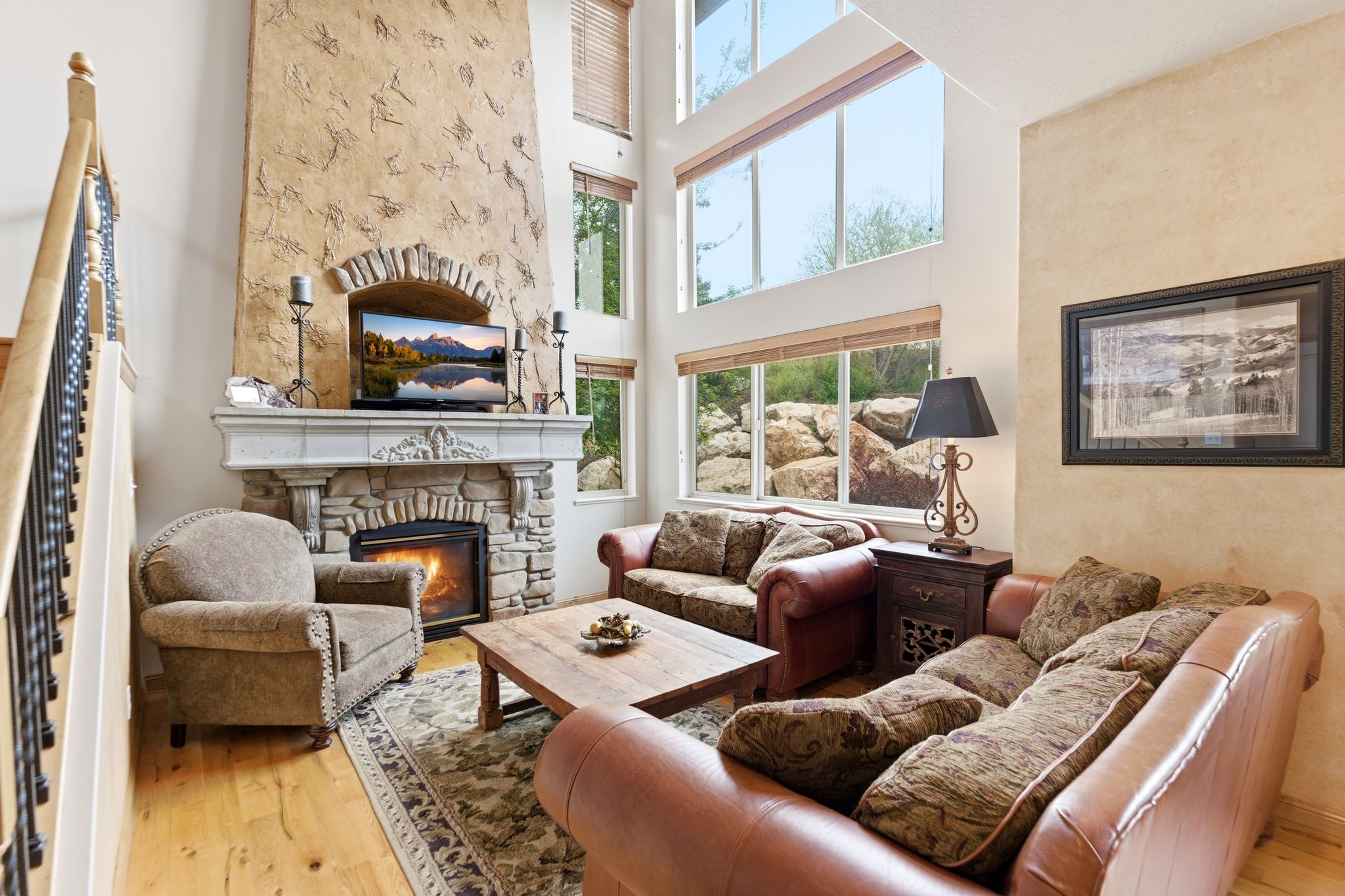 Spacious living area featuring a stone fireplace with a decorative mantel, a textured stucco accent wall, and high ceilings