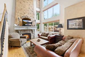 Spacious living area featuring a stone fireplace with a decorative mantel, a textured stucco accent wall, and high ceilings