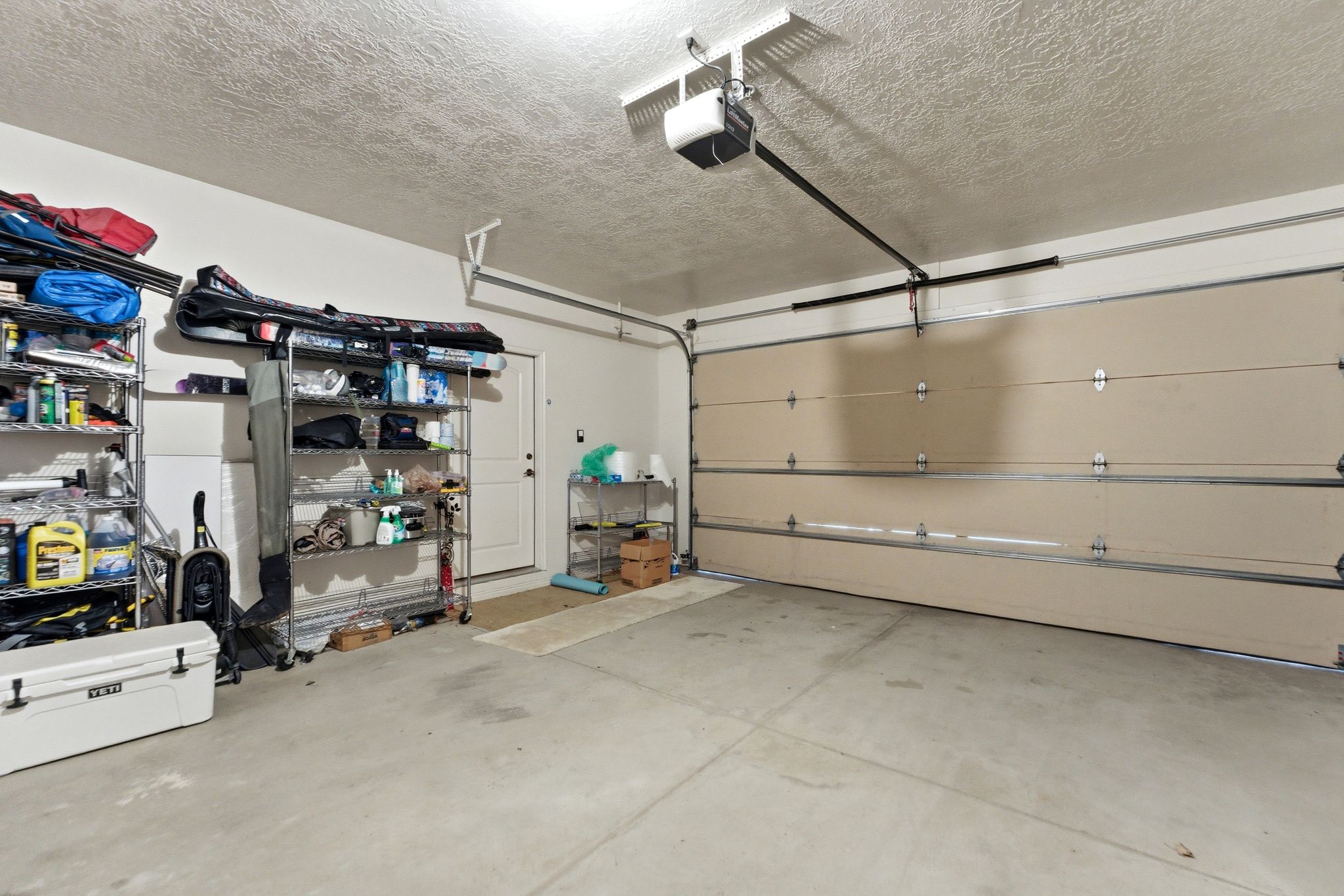 Two-car garage featuring a sectional garage door, concrete flooring, and a ceiling-mounted garage door opener