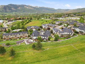 Expansive hillside community featuring multiple multi-story townhome-style residences with dark roofing, light-toned siding, and surrounding green spaces