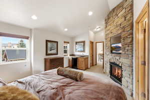 Stone-clad fireplace with integrated media niche and built-in mini-bar with sink and cabinetry