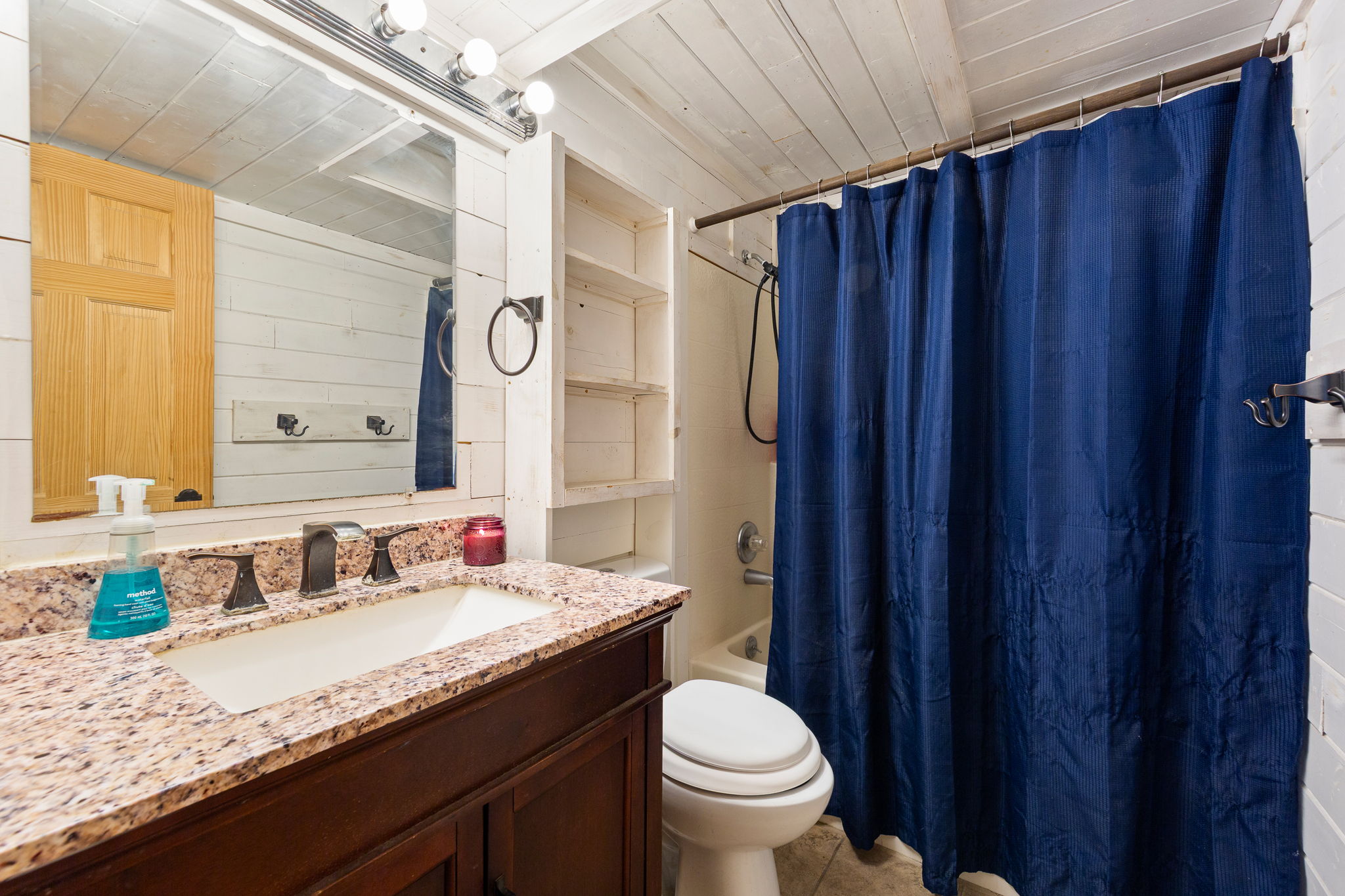 Bathroom vanity featuring a speckled countertop, undermount sink, and dark wood-finish cabinetry