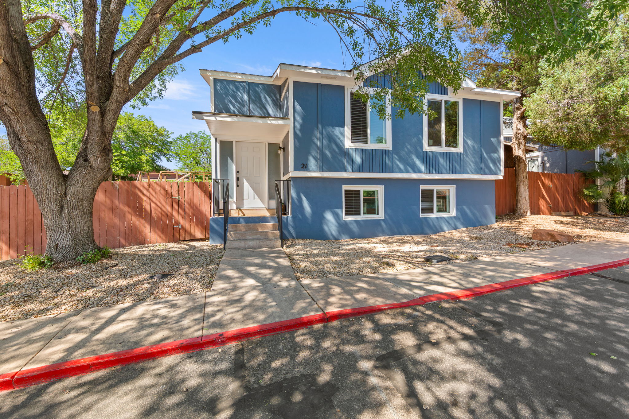 Contemporary blue exterior with white trim, featuring multiple large windows and a covered entry