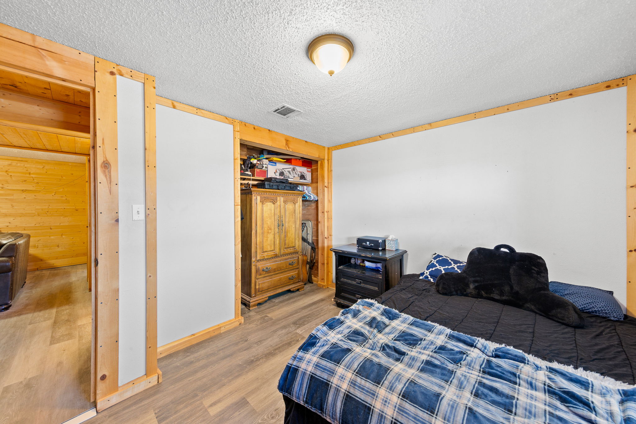 Room featuring wood-finish flooring and white walls with natural wood trim accents
