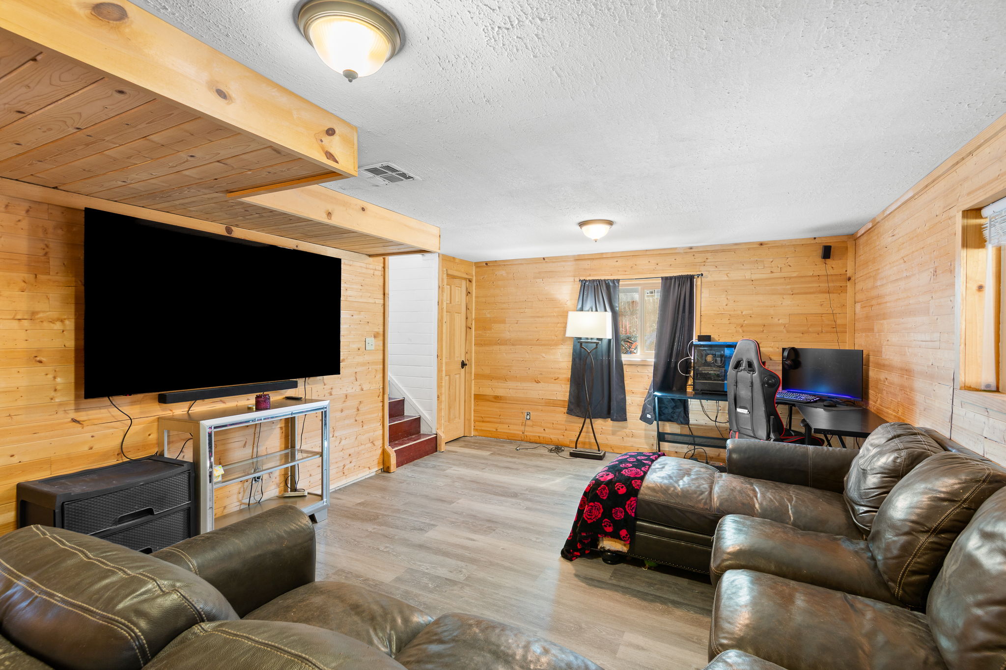 Spacious room featuring wood-paneled walls and a matching wood-paneled ceiling accent