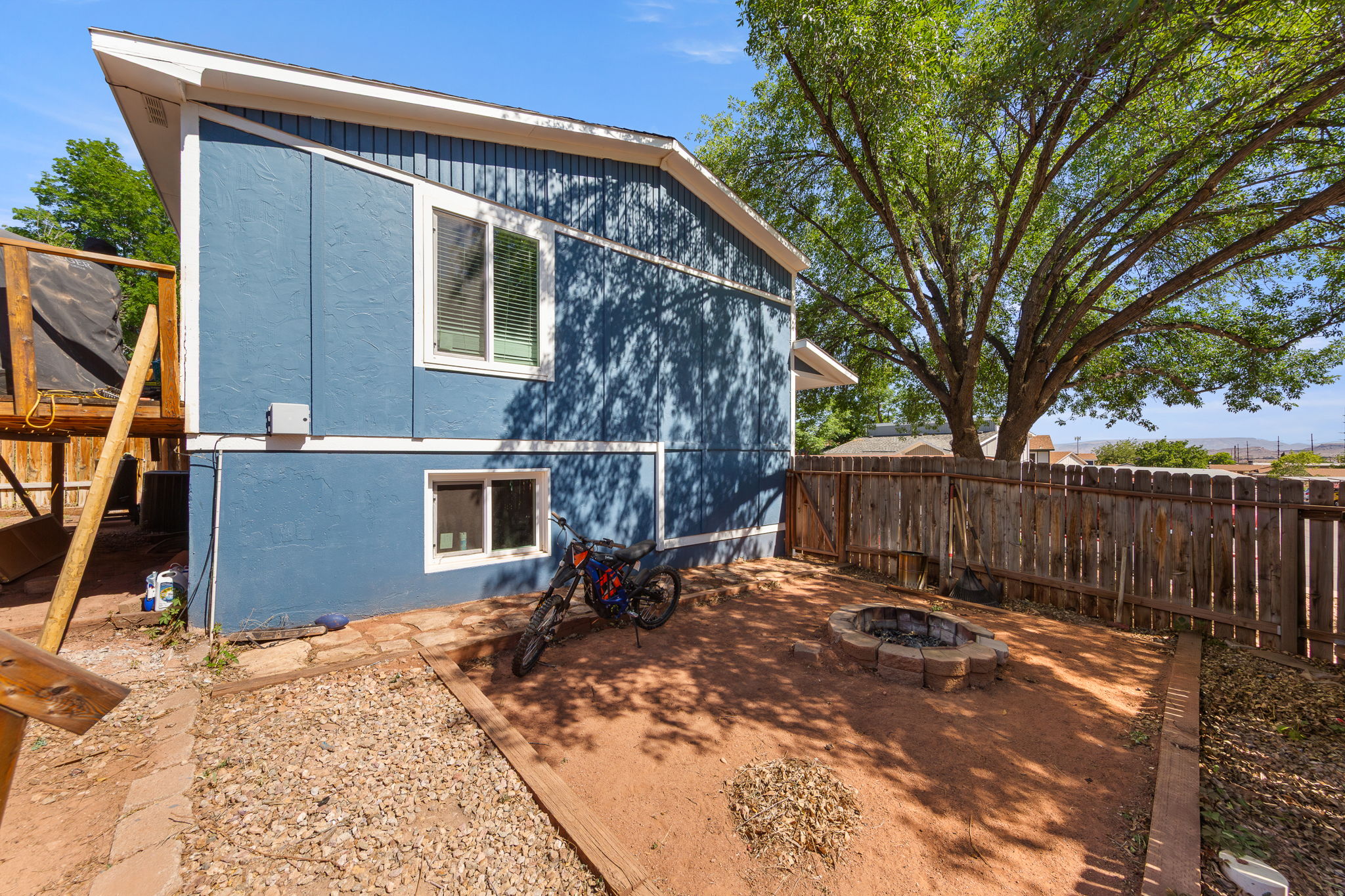 Backyard featuring a built-in fire pit, privacy fencing, and mature trees