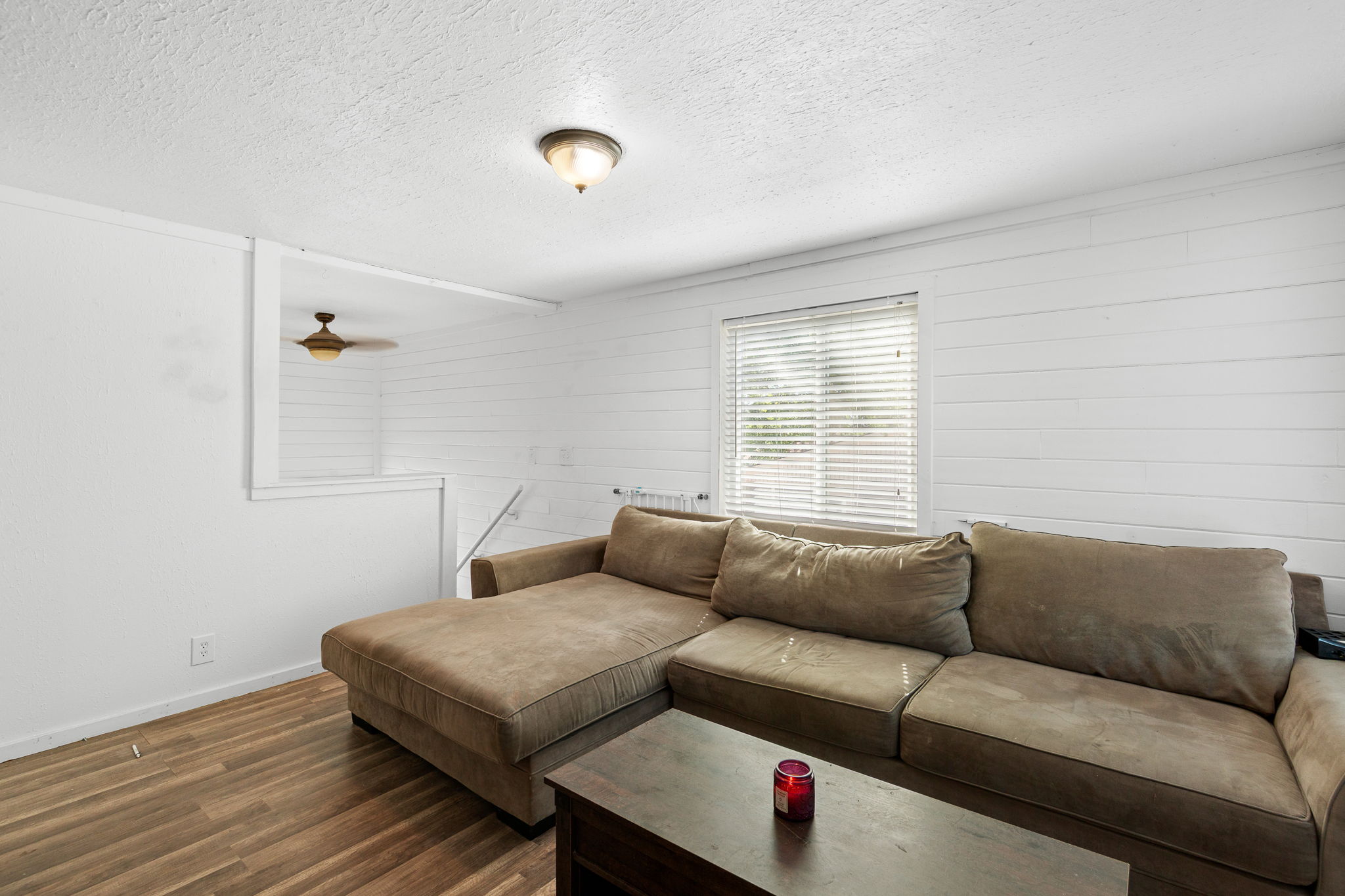 Living area with wood-finish flooring and white shiplap accent wall