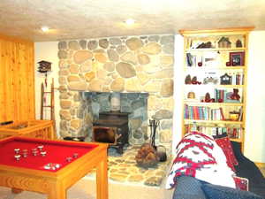 A wood burning stove heats the whole cabin in the winter and has a gray river rock hearth and pedestal.