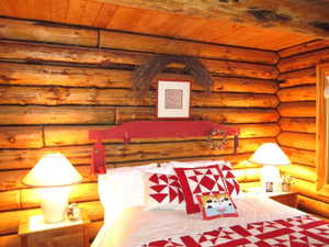 A queen bed, red headboard & two night stands are on the north wall.