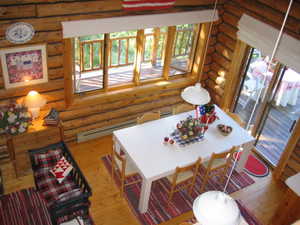 The dining area has an extendable custom built table, suspended factory lighting fixture and view windows. The sliding door opens to the deck.