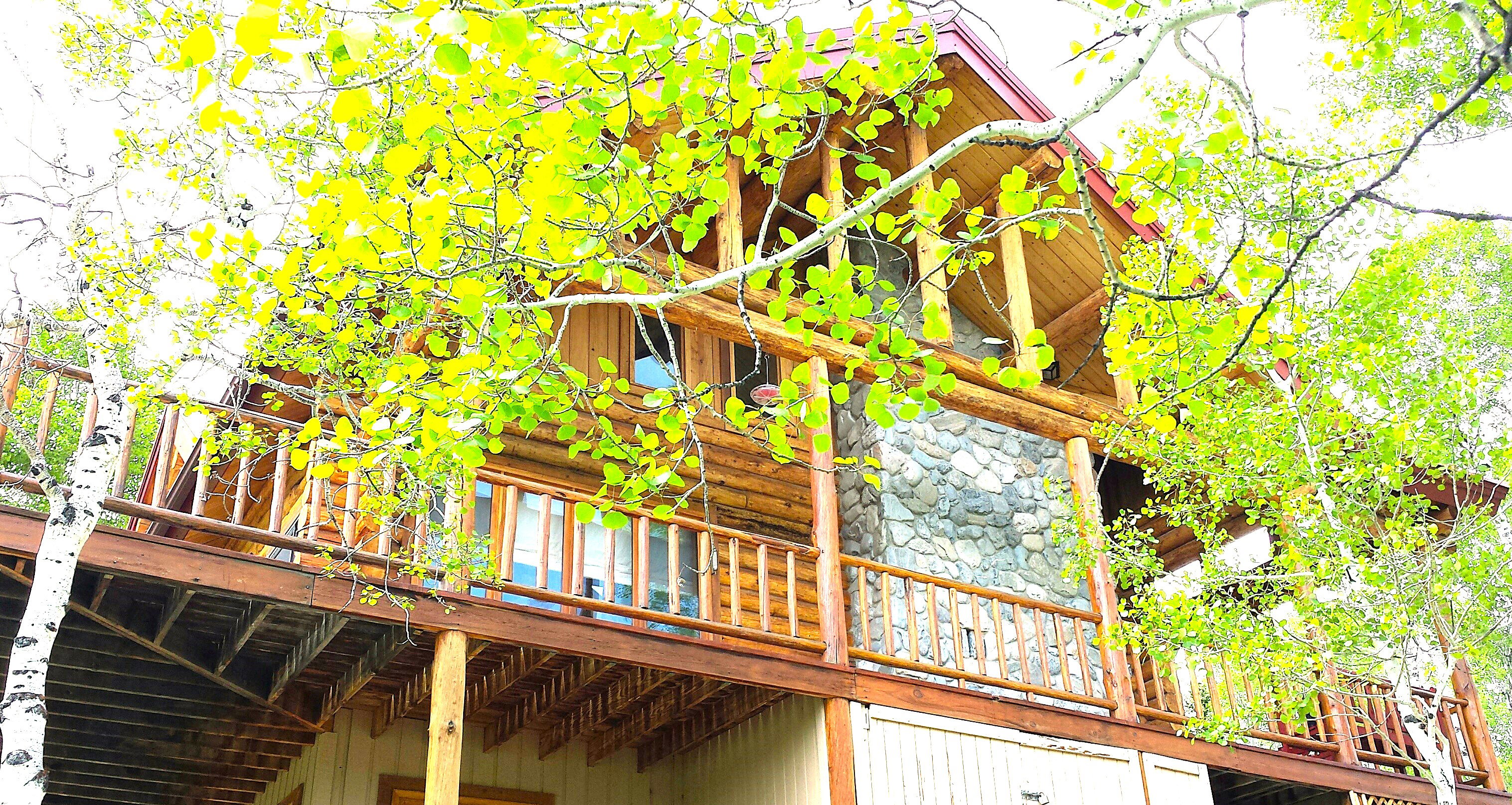 The covered deck on the south side of the cabin. There is a place for a hot tub by the window, and a storage shed is located below the deck.