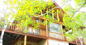 The covered deck on the south side of the cabin. There is a place for a hot tub by the window, and a storage shed is located below the deck.