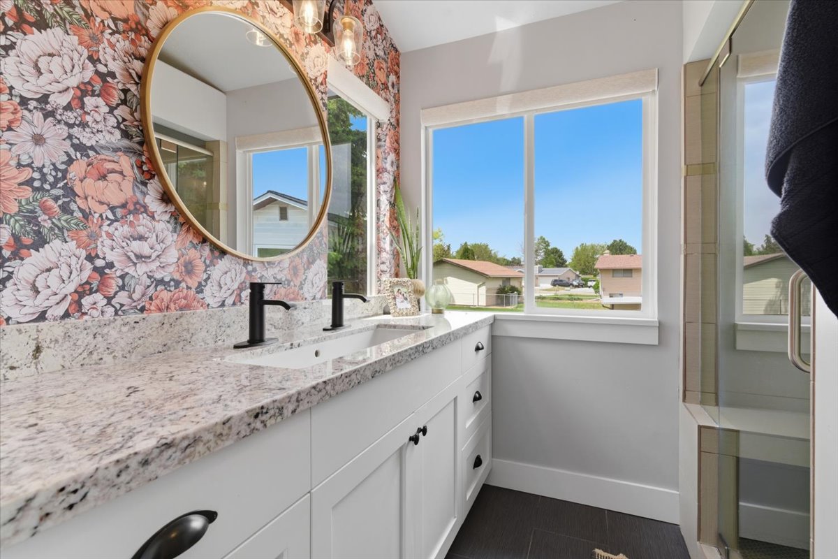 Dual vanity with white cabinetry, granite countertop, matte black fixtures, walk-in shower with dual shower heads