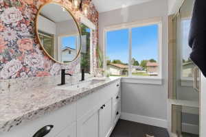 Dual vanity with white cabinetry, granite countertop, matte black fixtures, walk-in shower with dual shower heads