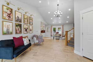 Open-concept living space featuring tile flooring, a vaulted ceiling with recessed lighting, and a contemporary chandelier
